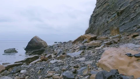 Wild stony beach with huge cliff on rainy day on sea coast. Stock-Footage 116659587