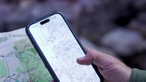 Wilderness navigation, close-up shot of topographical map and navigational app Stock Footage 344984652