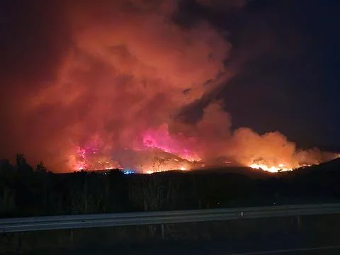Wildfire burning mountainside creating intense smoke and destruction Stock Photos