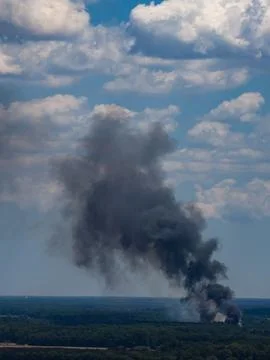 Wildfire burns distant forest trees. Wildfire smoke forms black plume. Wildfi 스톡 사진