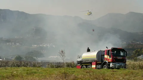 Wildfire fire tender, fire fighters, helicopter hanging bucket drops water Stock-Footage 171873035