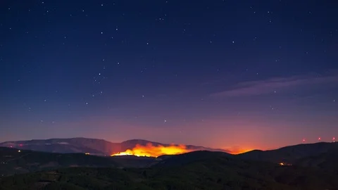 Wildfire over a mountain range at night - Timelaps 動画素材 100817583