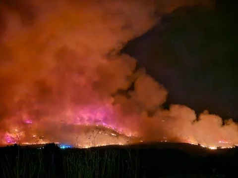 Wildfire raging over hillside spreading intense smoke Stock Photos