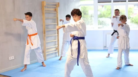 Willing junior boy wearing kimono training karate techniques in group during Stock Footage 341428826