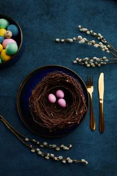 Willow branch, easter eggs in nest and tableware Stock Photos