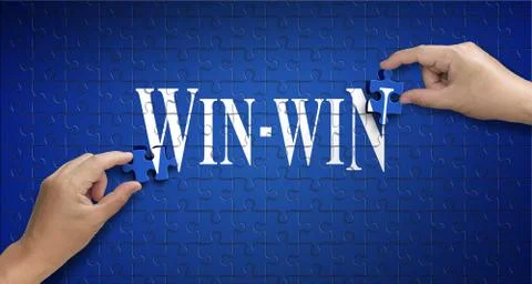 Win win word on Jigsaw puzzle. Man hand holding a blue puzzle to complete the Stock Photos