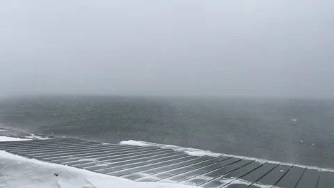 Wind and snow drifting across sea during winter blizzard Stock Footage 319574247