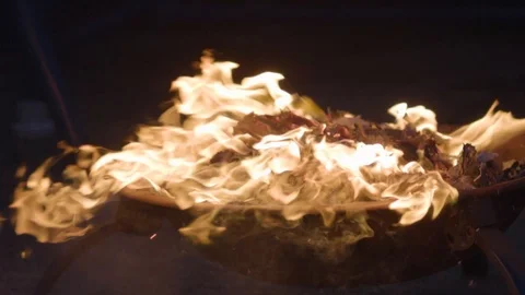 Wind blowing a burning piece of newspaper out of a fire pit onto the Stock Footage 112191579