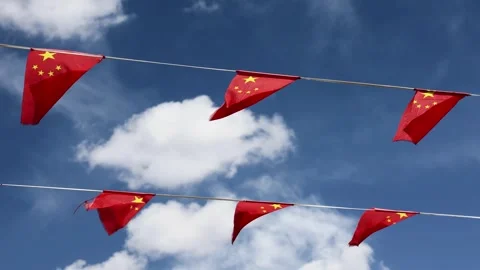 Wind blowing China flags fixed to two string lines against blue sky Stock Footage 282040389
