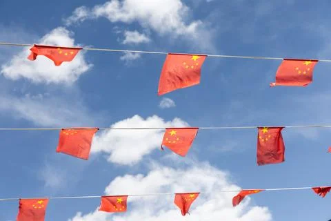 Wind blowing China flags fixed to three lines against blue sky Stock Photos
