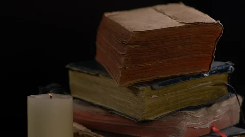 Wind Blowing Flame Of A White Candle with Old Books on Background Video stock 130145033