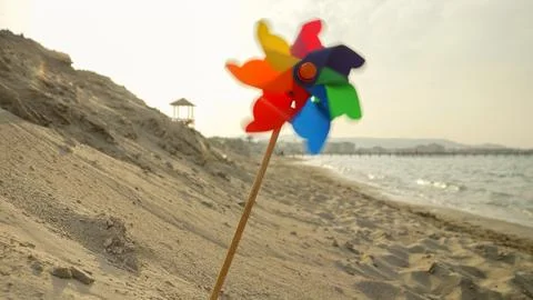 Wind blowing gently, a pinwheel turns on a sandy beach, capturing the spiri.. Stock Photos
