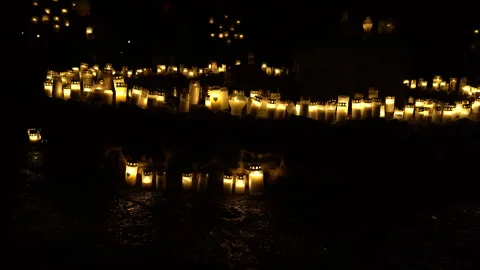 Wind blowing on hundreds of lit grave candles at night at graveyard Stock Footage 289048117