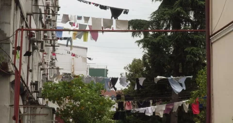 Wind blowing laundry drying on clothesline between apartment buildings Stock Footage 292047269