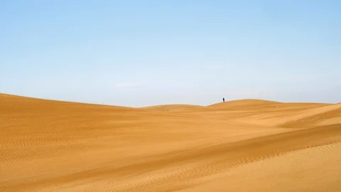 Wind blowing over sand dunes with a couple in the distance. Stock Footage 106071923
