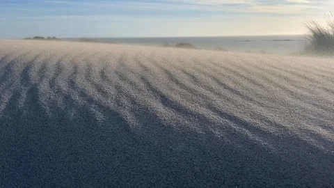 Wind blowing over sand dunes under a clear sky Stock Footage 289475147