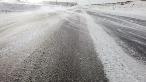 Wind blowing snow over the road. snowdrift close up. winter blizzard Stock Footage 157309225