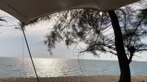 The wind is blowing the tent tarp with the glittering sea Stock Footage 196979109