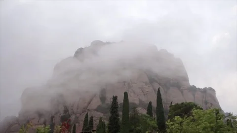 Wind blown clouds circulate round a mountain top in Spain. 스톡 동영상 77470612