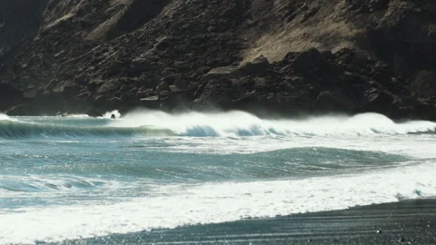 Wind blown waves breaking below sea cliffs on Vik beach Iceland Video stock 348027495