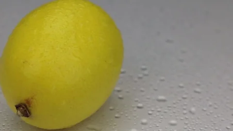 Wind blows away the drops of water from a rotating lemon. Stock Footage