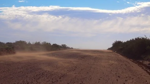 Wind blows dust along a lonely dirt road in the desert. 库存影片 79506183