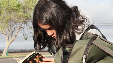 Wind blows kid's hair while she reads Stock Footage 155387930