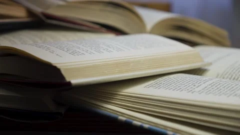 Wind blows open book page on scattered pile of reference literature Video stock 305459428