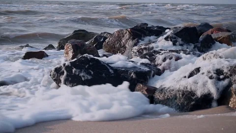 The wind blows the waves from black granite stones into the sea Stock Footage 110871730