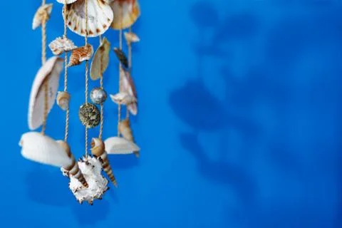 A wind chime with shells on a blue background Stock Photos