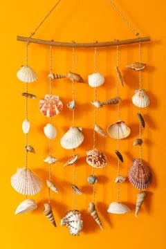 A wind chime with shells on a yellow background Stock Photos