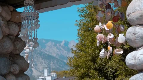 Wind chimes made from colorful shells on a background of blue sky, mountains Stock Footage 323845533