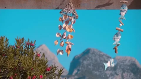 Wind chimes made from shells sway in the wind on a background of blue sky Stock Footage 323836897