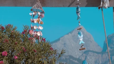 Wind chimes made from shells sway in the wind on a background of blue sky Vídeos de archivo 323855458