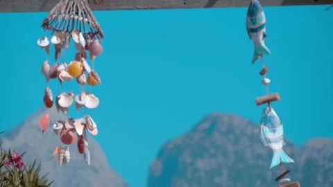 Wind chimes made from shells sway in the wind on a background of blue sky  Stock Footage 323905196