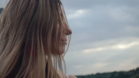 The wind develops long hair of a cute, beautiful girl. Face close-up Video stock 129221383