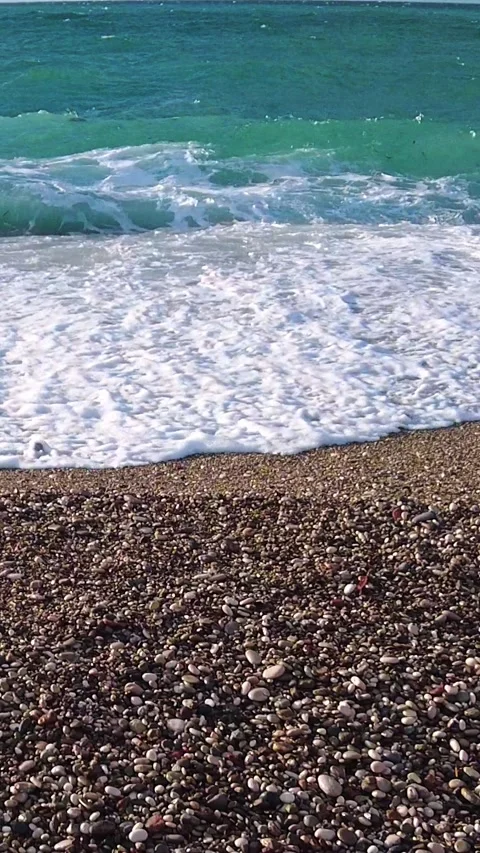 Wind-driven sea foam spreading across Konyaalti pebble shoreline Video stock 323589053