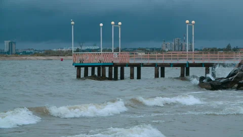 The wind drives the waves to the shore, a boat dock is visible in the distance Stock Footage 289808634