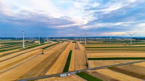 Wind farm across patchwork fields under cloudy sky. Drone view with road, s.. Stock Photos