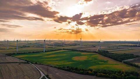 Wind farm beneath an orange sunset and sunbeams. Clouds partially cover the.. Stock Photos