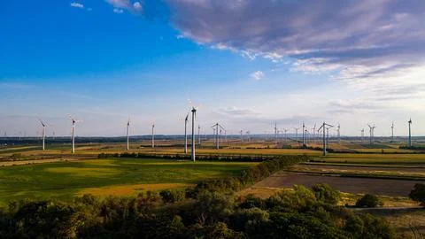Wind farm beyond tree belts beneath a cloud bank. Rows of towers stand abov.. Stock Photos