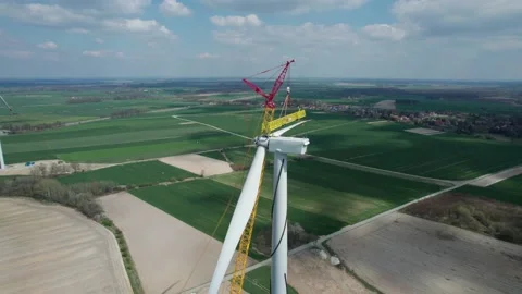 The wind farm during construction, the crane lifts a huge propeller, which th Stock Footage 196113451