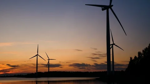 Wind farm, medium long shot silhouettes of four wind turbines spinning 스톡 동영상 117372498