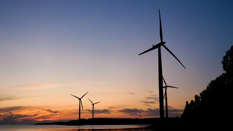 Wind farm, silhouettes of four wind turbines spinning at dusk 動画素材 117373248