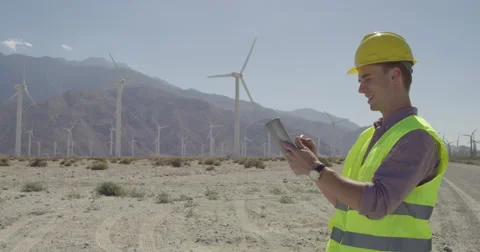 Wind farm technician with computer tests wind with finger 4K Stock Footage 63778909
