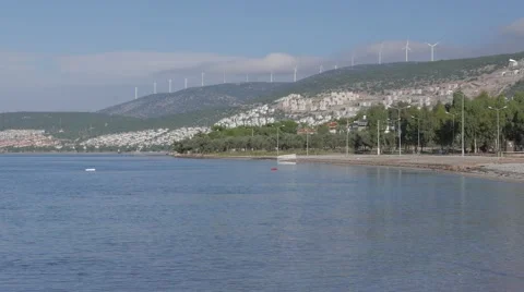Wind farm on the top of the mountains surrounded by clouds with sea and a resort Stock Footage 61750294