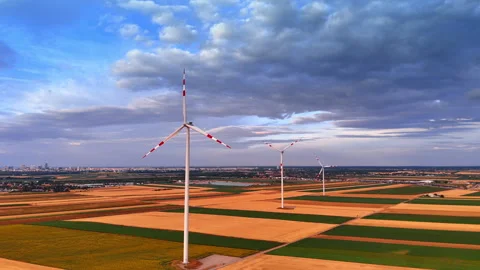 Wind farm turbines crossing patchwork fields beneath storm clouds Stock Footage 339745770