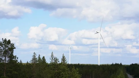 Wind farm, two wind turbines with pine trees in foreground Video stock 117354313