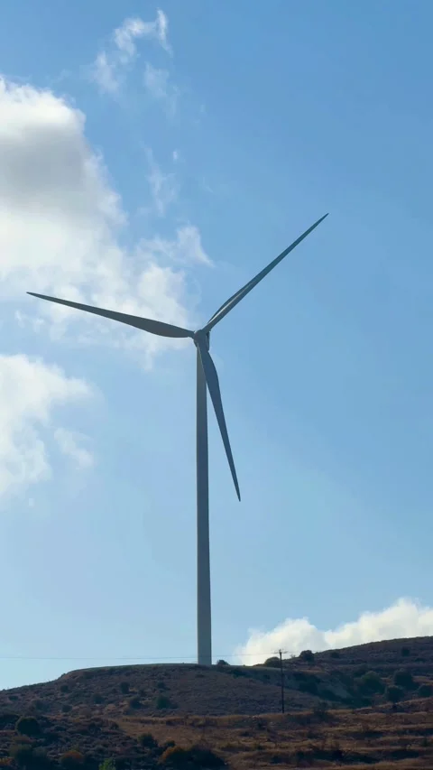 Wind generator rotating on a hill under blue sky Видео 334593248