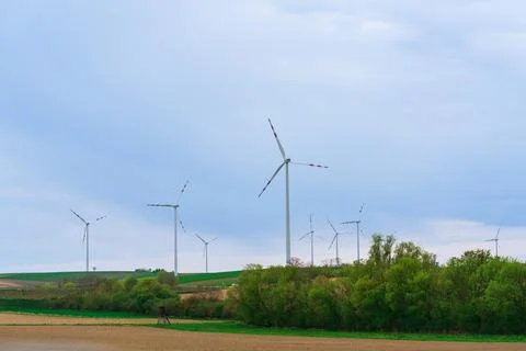 Wind generators against a blue sky stand by a country road with a white car b Stock Photos